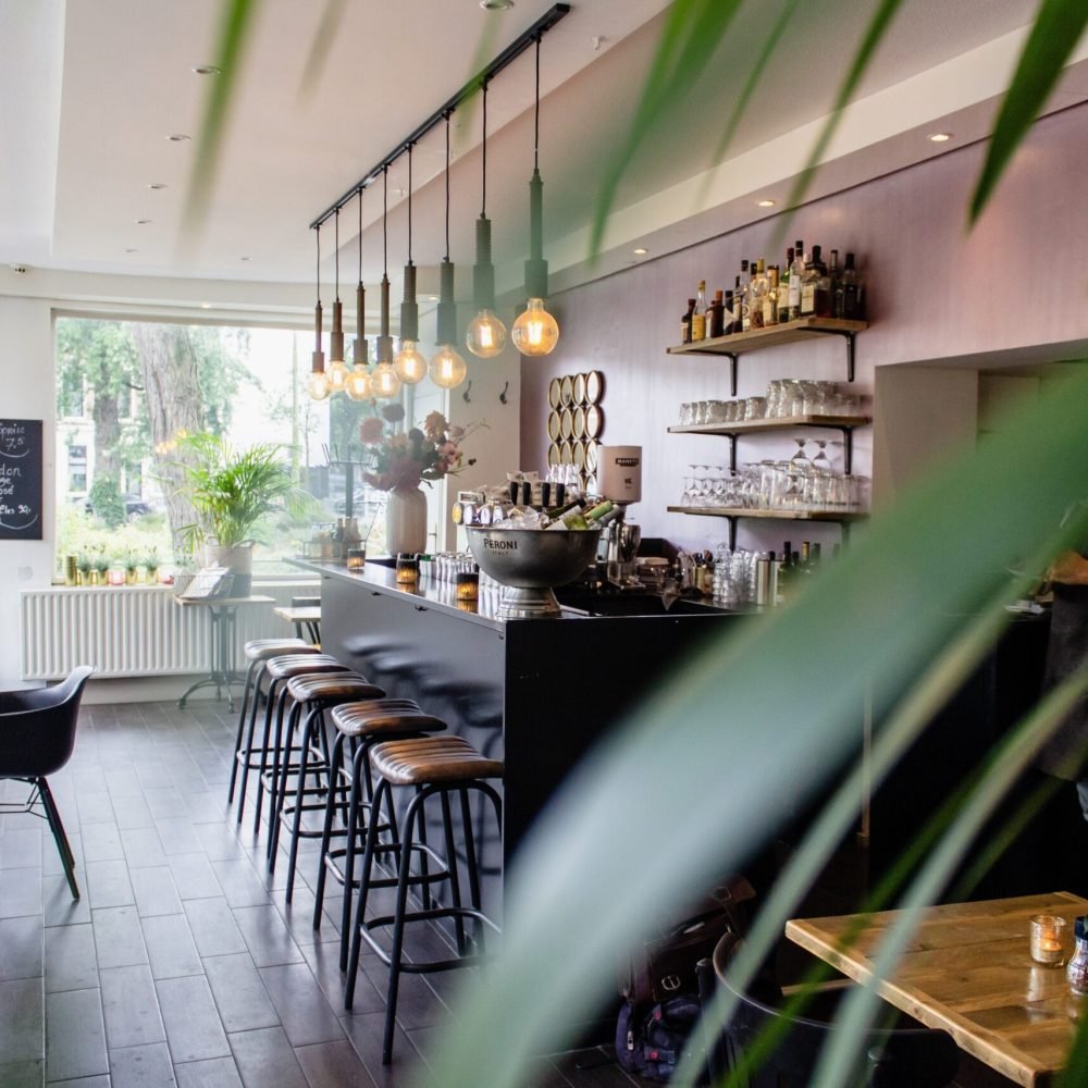 An interior shot of a cafe with chairs near the bar with wooden tables